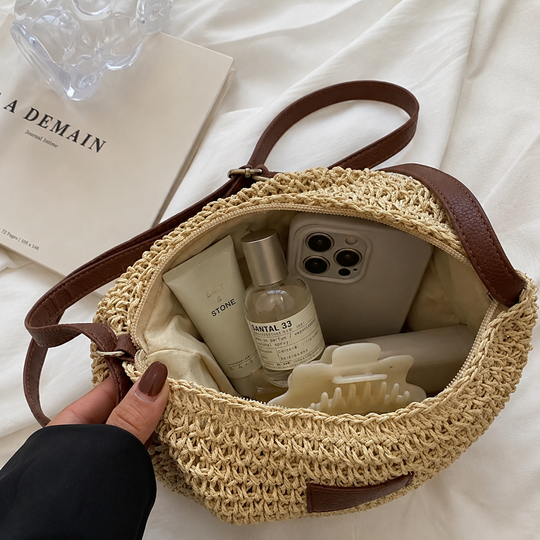 Close-up of woven bag interior with phone, lotion, and perfume on a fabric surface.