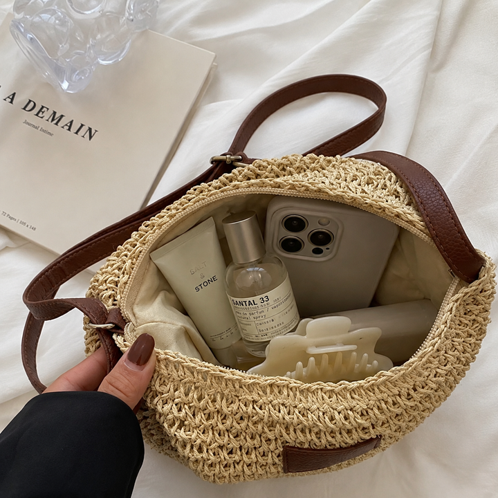 Close-up of woven bag interior with phone, lotion, and perfume on a fabric surface.