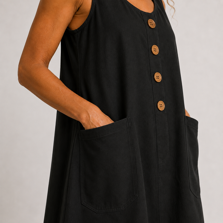 Close-up of a black dress with buttons and pocket, worn in a studio setting.
