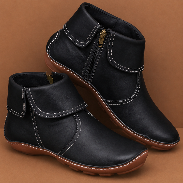 Black orthopedic waterproof boots with side zippers placed on a tan background.