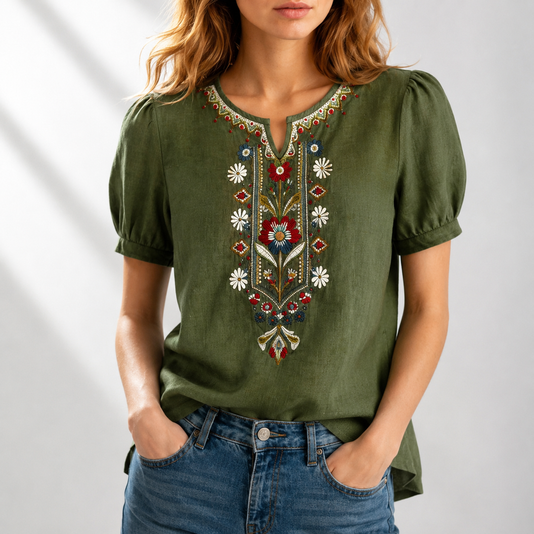 Woman in a green blouse featuring intricate floral embroidery, puff sleeves, set in a well-lit studio.