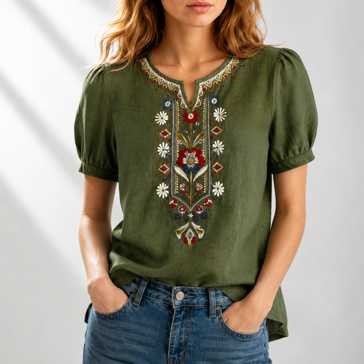 Woman in a green blouse featuring intricate floral embroidery, puff sleeves, set in a well-lit studio.