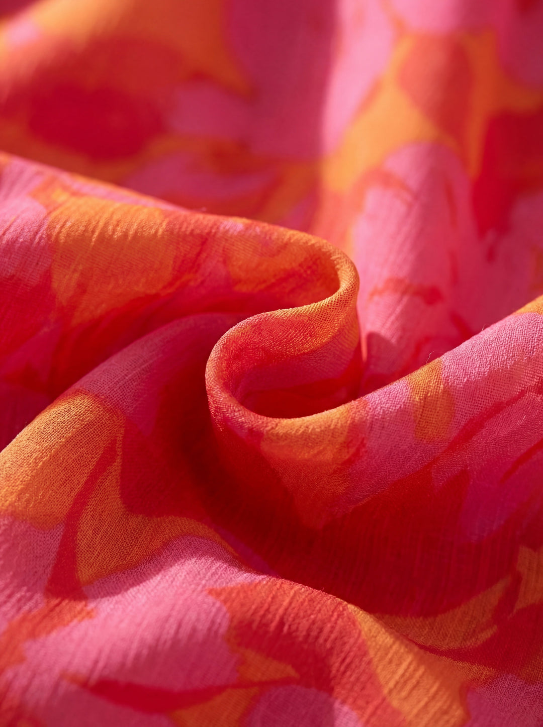 Close-up of pink and orange floral fabric, showcasing vivid patterns and soft textures in natural light.