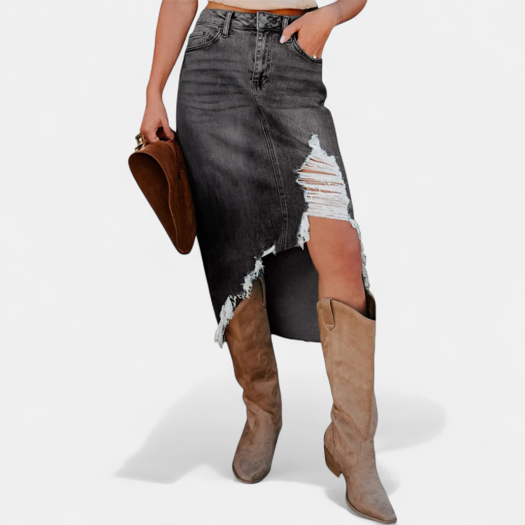 Gray distressed high-waist denim maxi skirt with a brown clutch and tan boots in a studio setting.