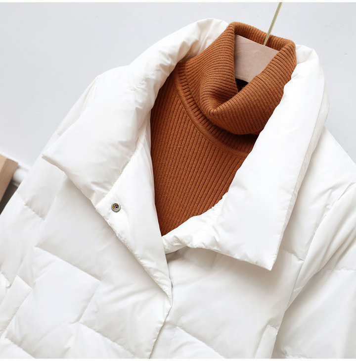 Close-up of a white quilted jacket with a brown turtleneck on a hanger against a white background.