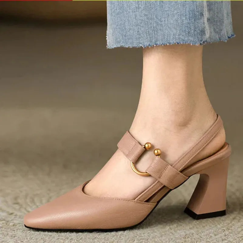 Beige heel with gold accents on foot in indoor setting, paired with light denim.