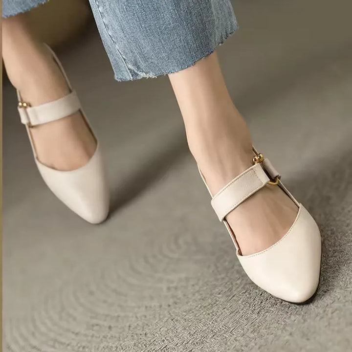 White heels with gold accents on feet on carpet, paired with light denim.