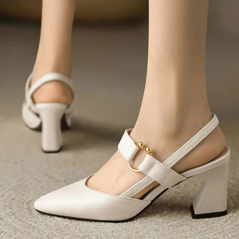 White heel with gold accents on foot in indoor setting, featuring a rear view.