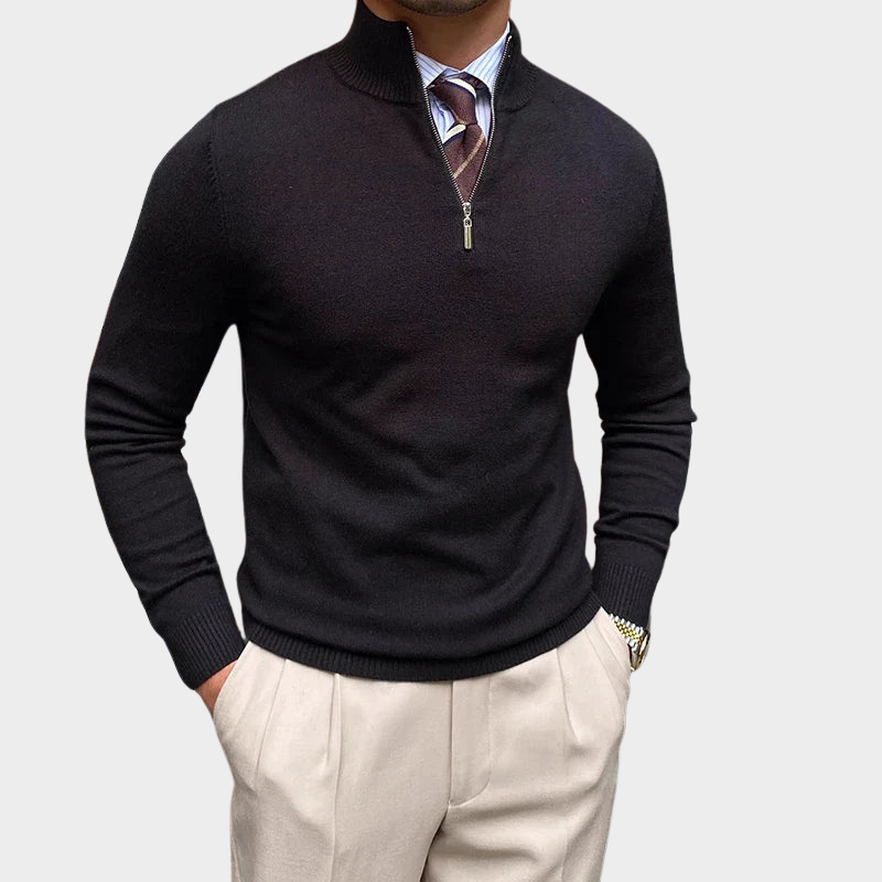Black half-zip sweater worn over a shirt and tie, paired with beige trousers in a studio setting.