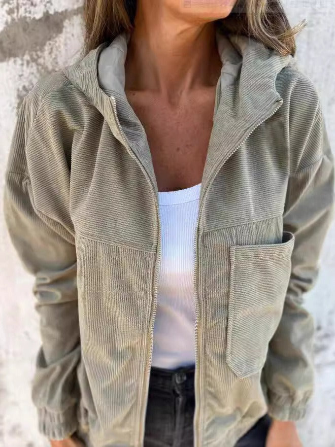 Khaki corduroy zip jacket over a white top, featuring a comfortable style and pocket accents, against a textured wall background.