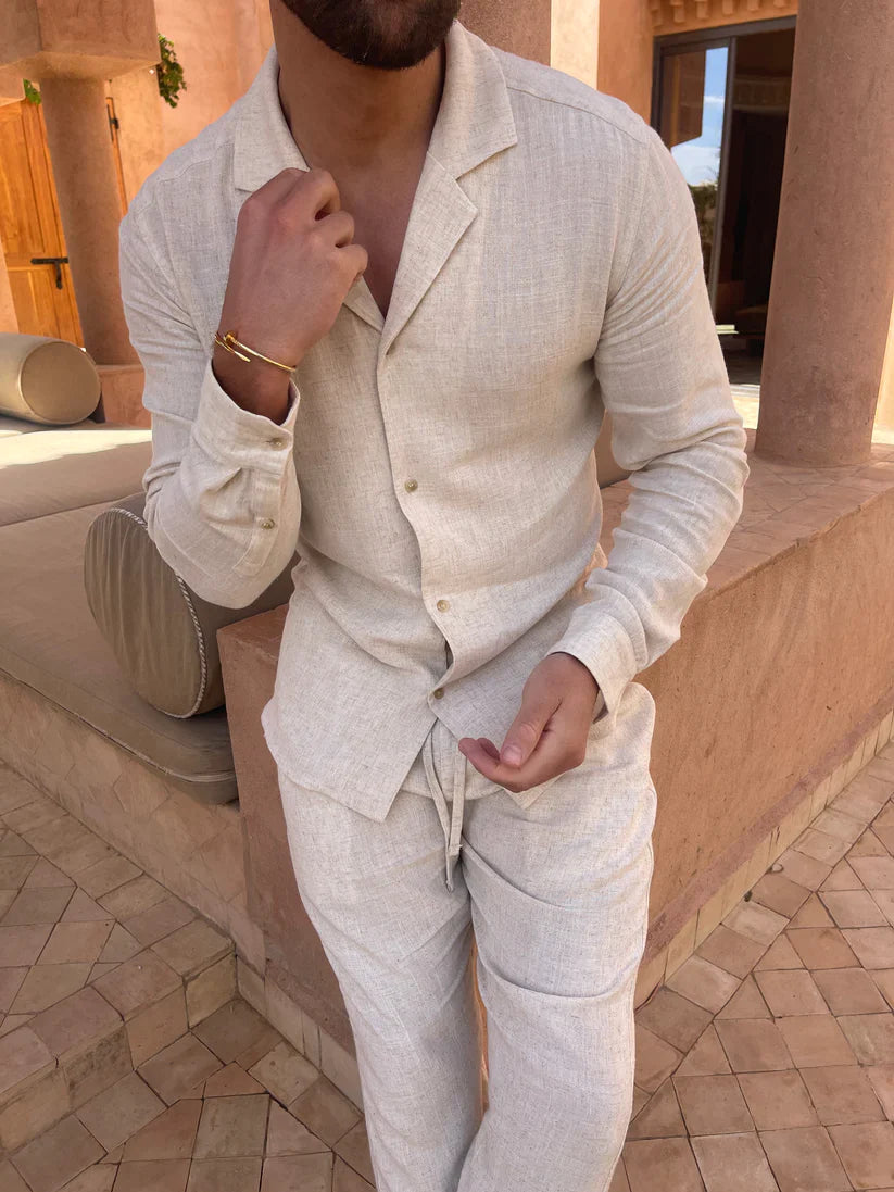 Stylish beige summer set with button-up shirt and drawstring pants, worn by a model in a sunlit outdoor setting with terracotta pillars.