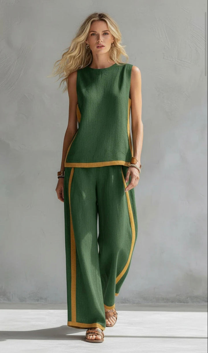 Model wearing a green two-piece set with yellow trim, standing in a gray textured studio.