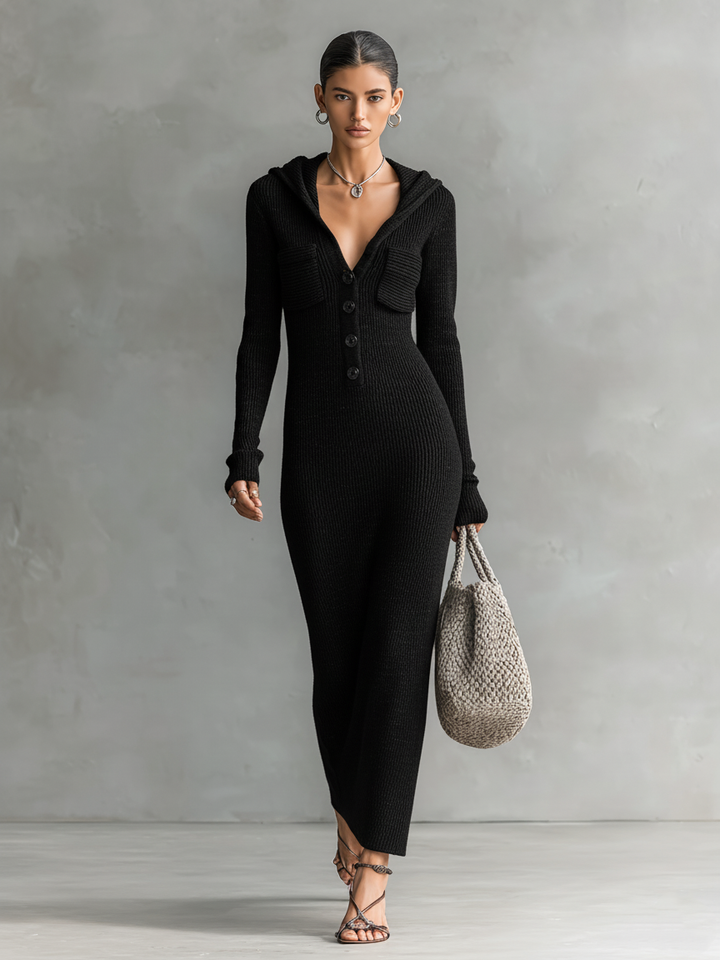 Model wearing a black slim-fit hooded maxi dress with button detail and a woven bag against a neutral background.