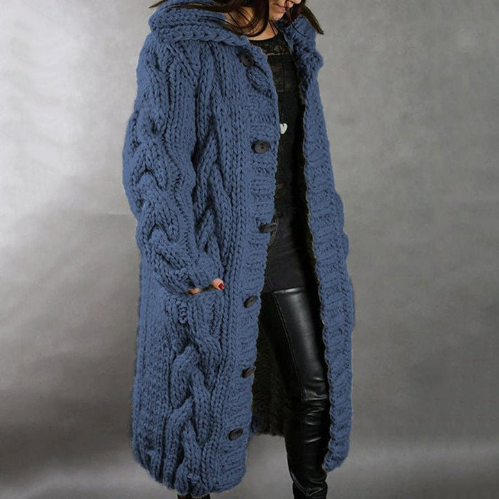 Blue knitted coat with buttons, worn by a person in leather pants, studio setting.