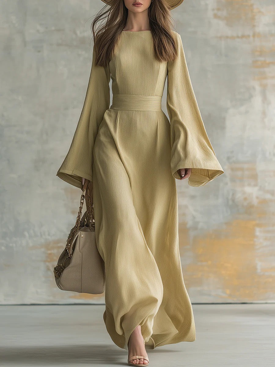 Elegant woman in a long, flowing beige dress with flared sleeves, carrying a beige handbag in a studio setting.