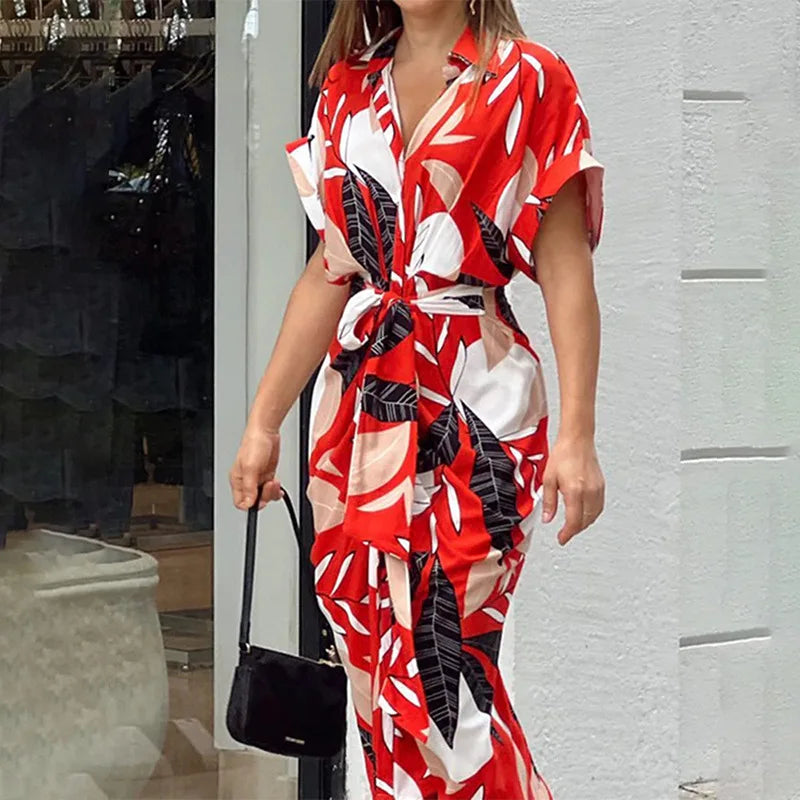 Vibrant red and white patterned wrap maxi dress with a tie waist, near an indoor plant and modern decor.
