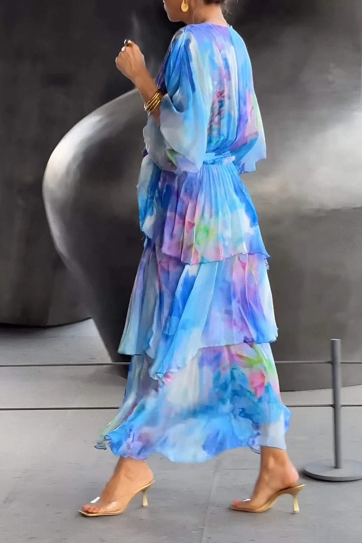 Back view of an elegant flowy dress in blue and purple hues, worn indoors. Metallic abstract sculpture in the background.