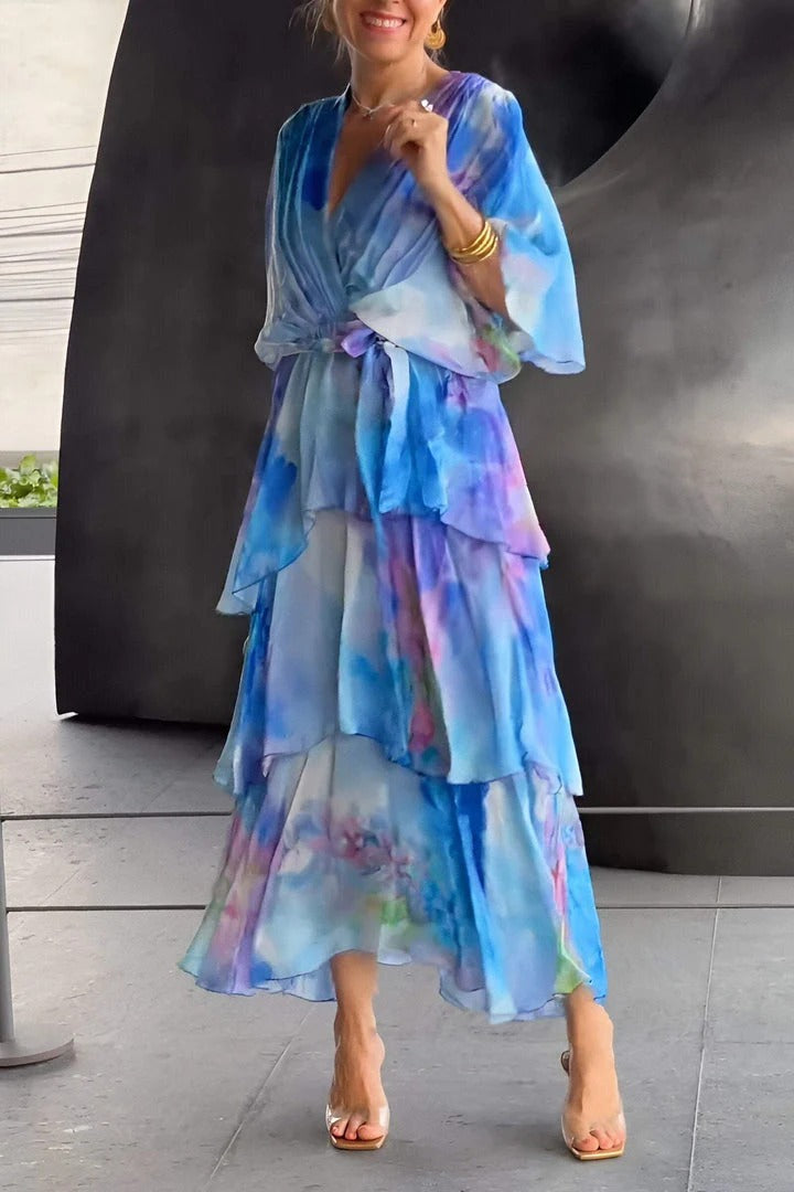Elegant flowy dress in blue and purple hues, worn by a person indoors. Metallic abstract background enhances the dress colors.