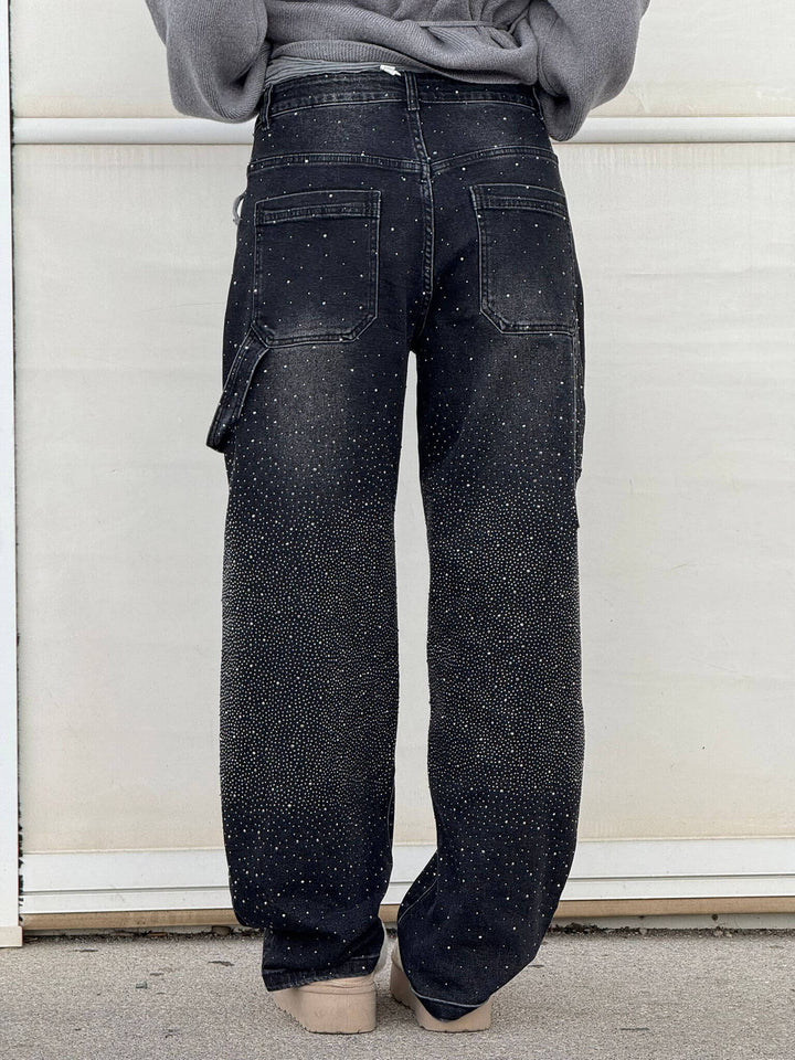Back view of black sparkling trousers paired with fur-lined slippers in an outdoor environment.