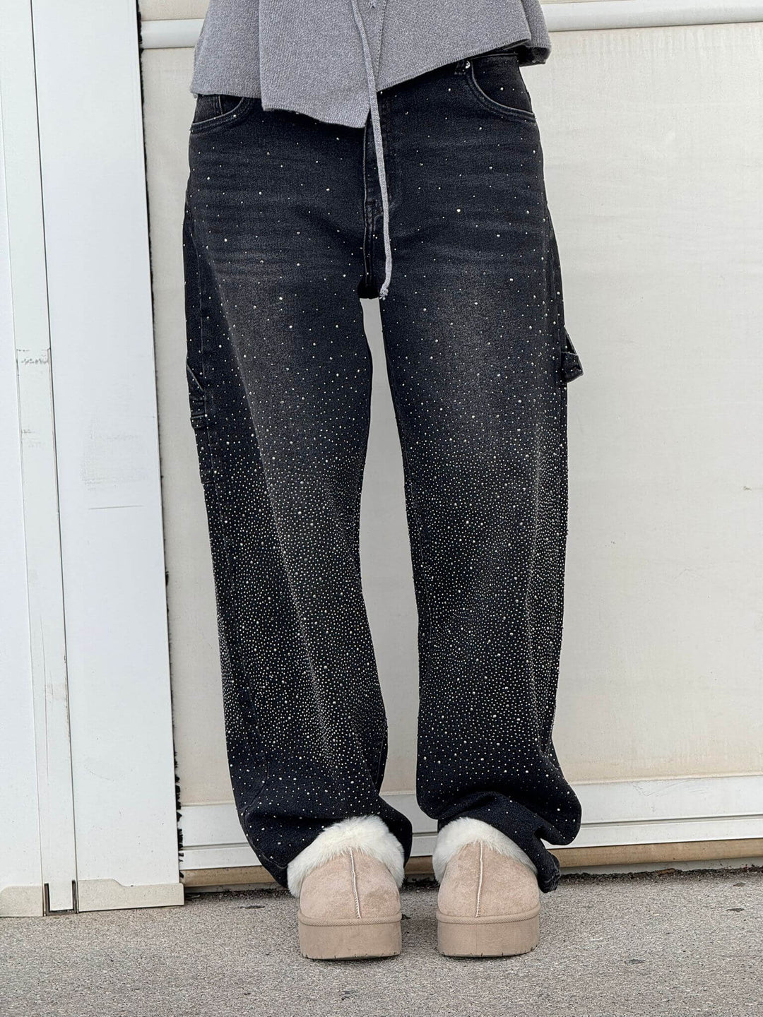 Black diamond-studded trousers with gray top and fur slippers set in an outdoor scene.