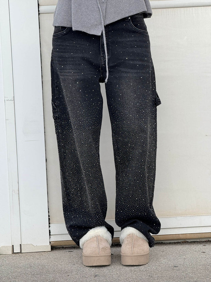 Black diamond-studded trousers with gray top and fur slippers set in an outdoor scene.