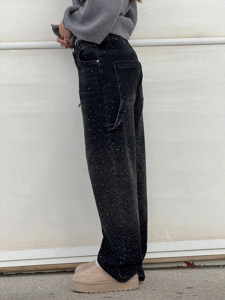 Side profile of black glittering trousers with fur slippers in an outdoor setting.