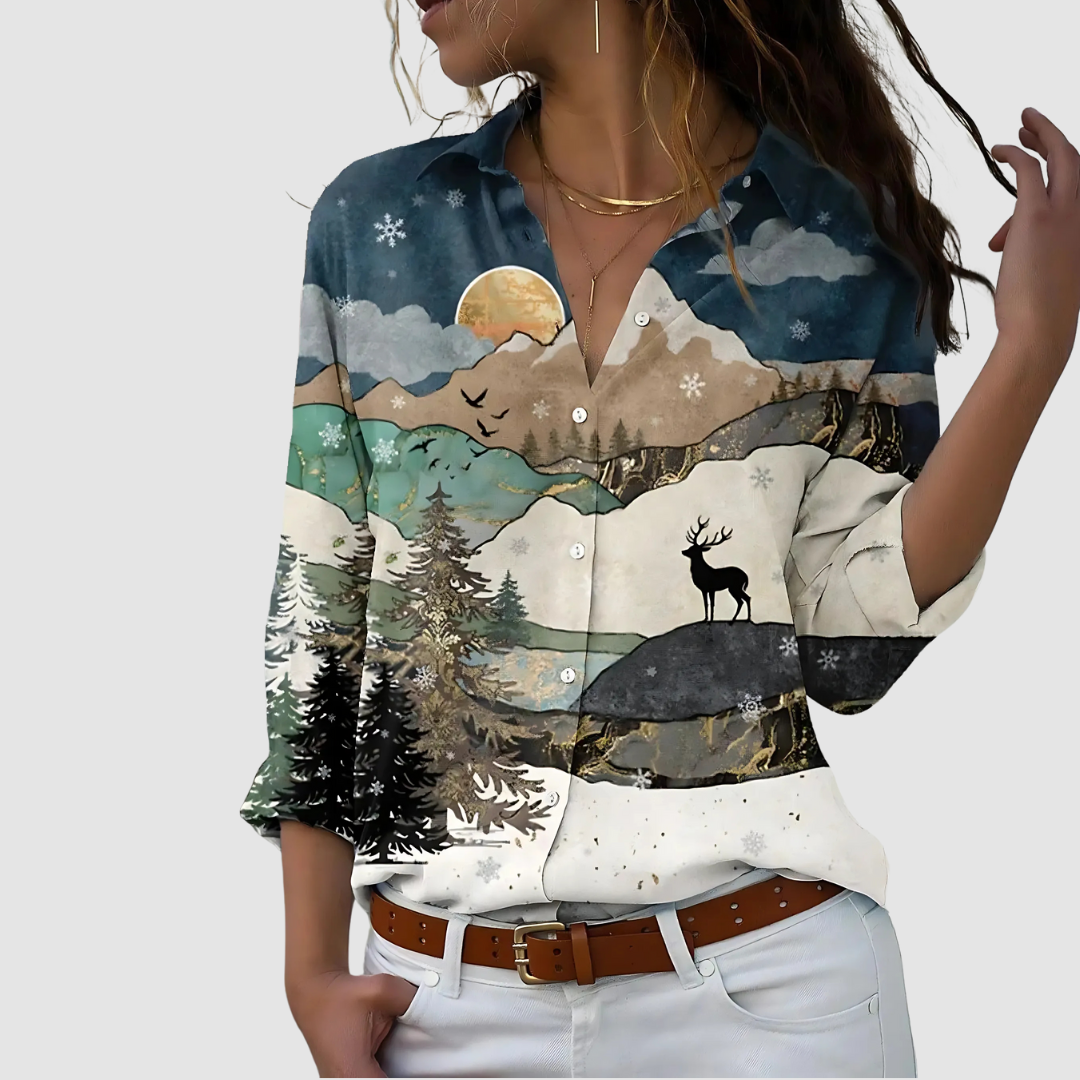 Soft blouse depicting a scenic mountain and deer landscape, styled with white pants against a plain backdrop.