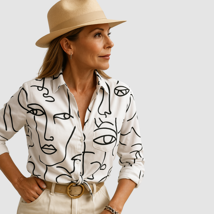 White blouse with abstract black line design, worn by person with tan hat; neutral studio background.