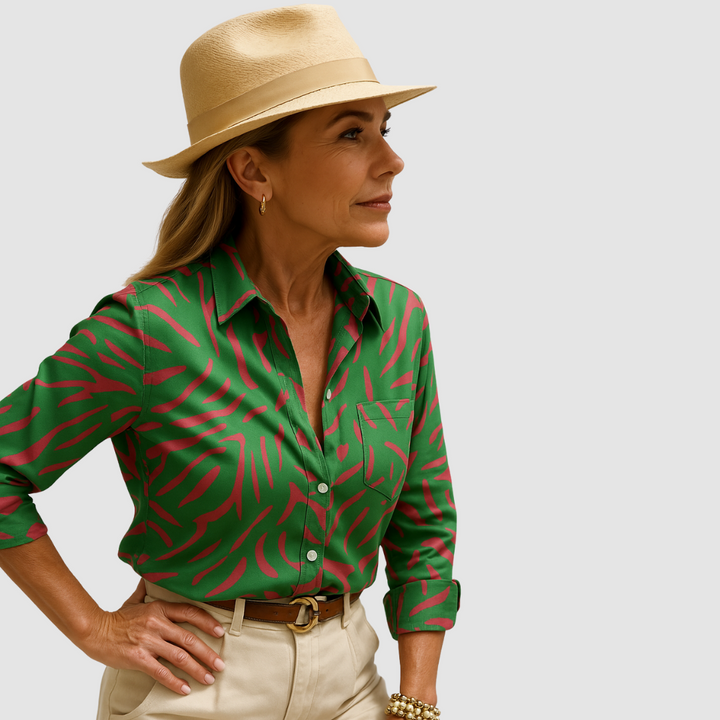 Green blouse with red abstract pattern, worn by person with tan hat; neutral studio background.