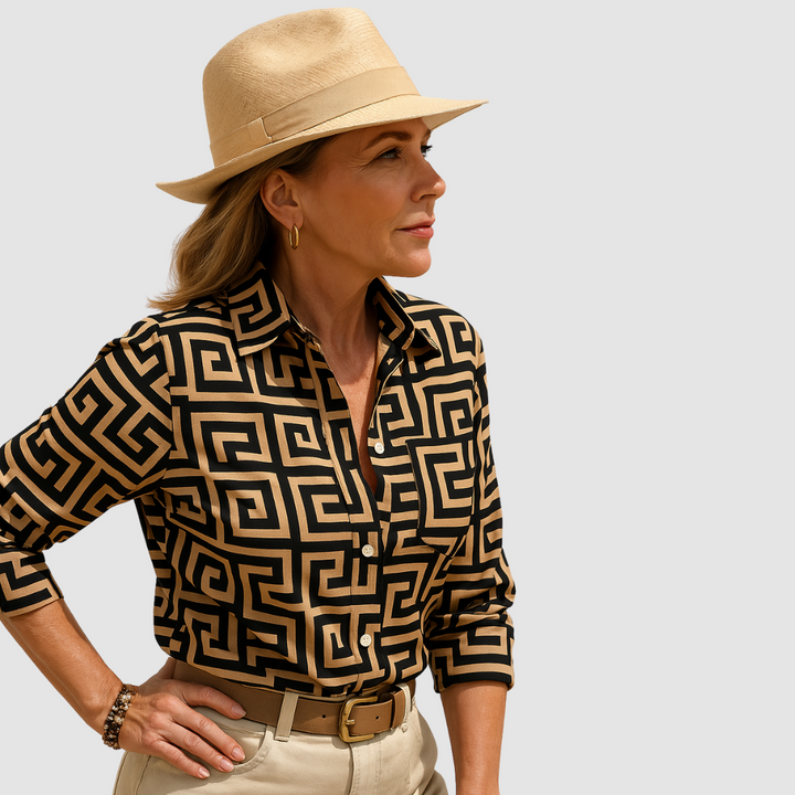 Black blouse with tan geometric pattern, worn by person with tan hat; neutral studio background.