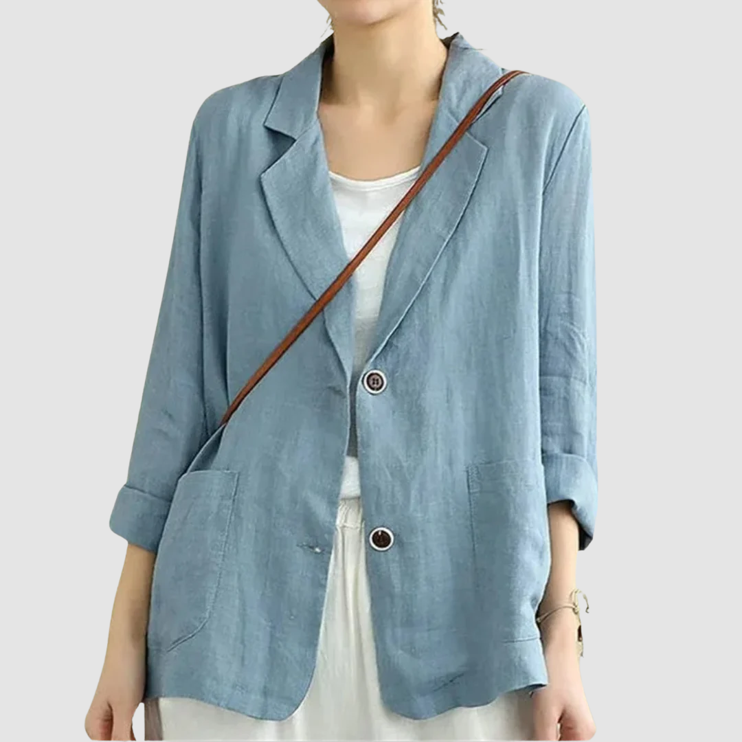 Casual chic blue blazer with rolled sleeves and front pockets styled with a white top, against a light gray background.