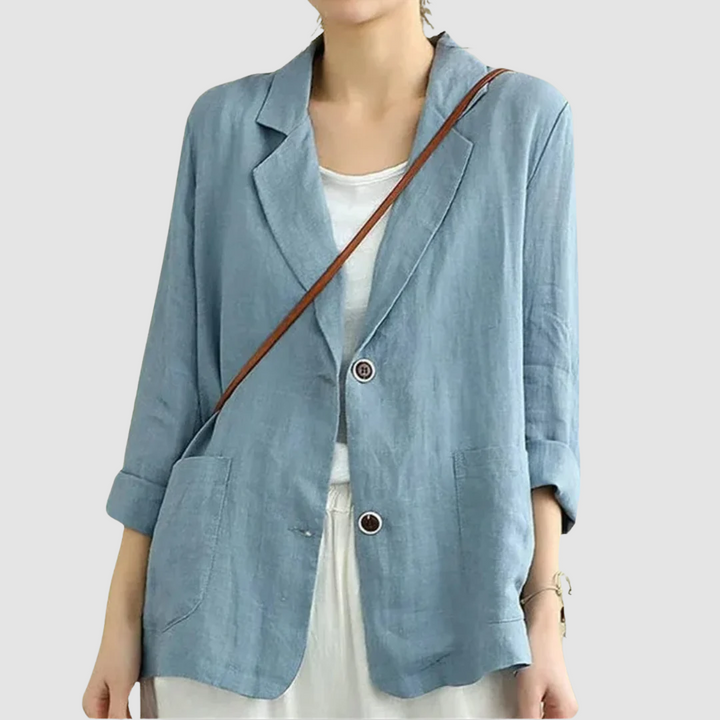 Casual chic blue blazer with rolled sleeves and front pockets styled with a white top, against a light gray background.