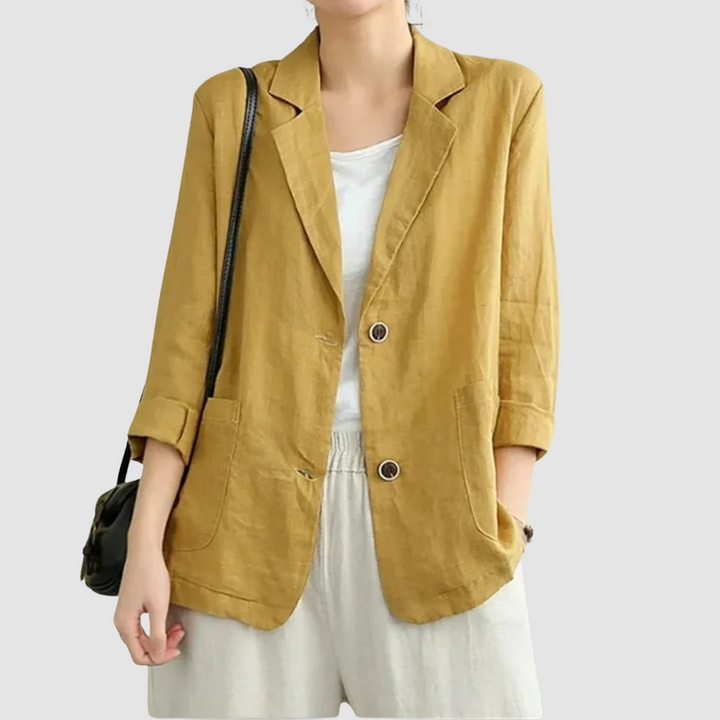 Casual chic yellow blazer with rolled sleeves and front pockets, worn with a white top and shorts, on a light gray background.
