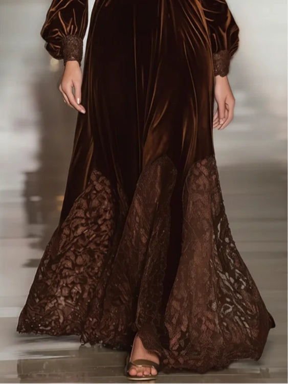 Close-up of a brown suede maxi dress with lace accents on the hem, shown in an indoor setting with a blurred background.