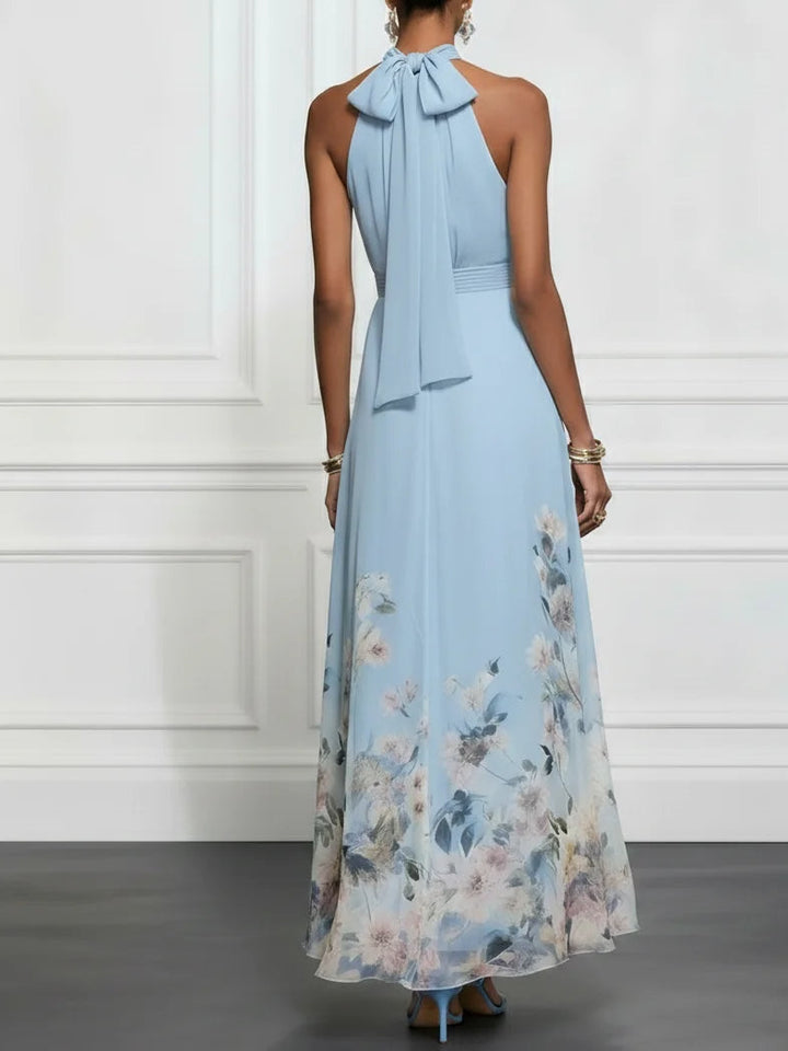Back view of a light blue maxi dress with floral detailing and bow tie neck in a studio setting.