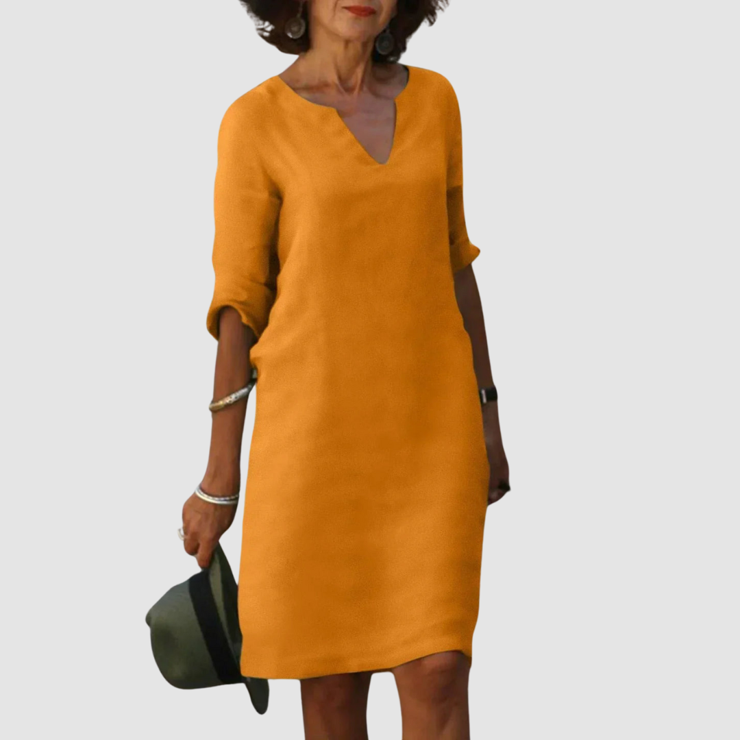 Elegant orange V-neck dress with mid-length sleeves, modeled with hat and jewelry on neutral background.