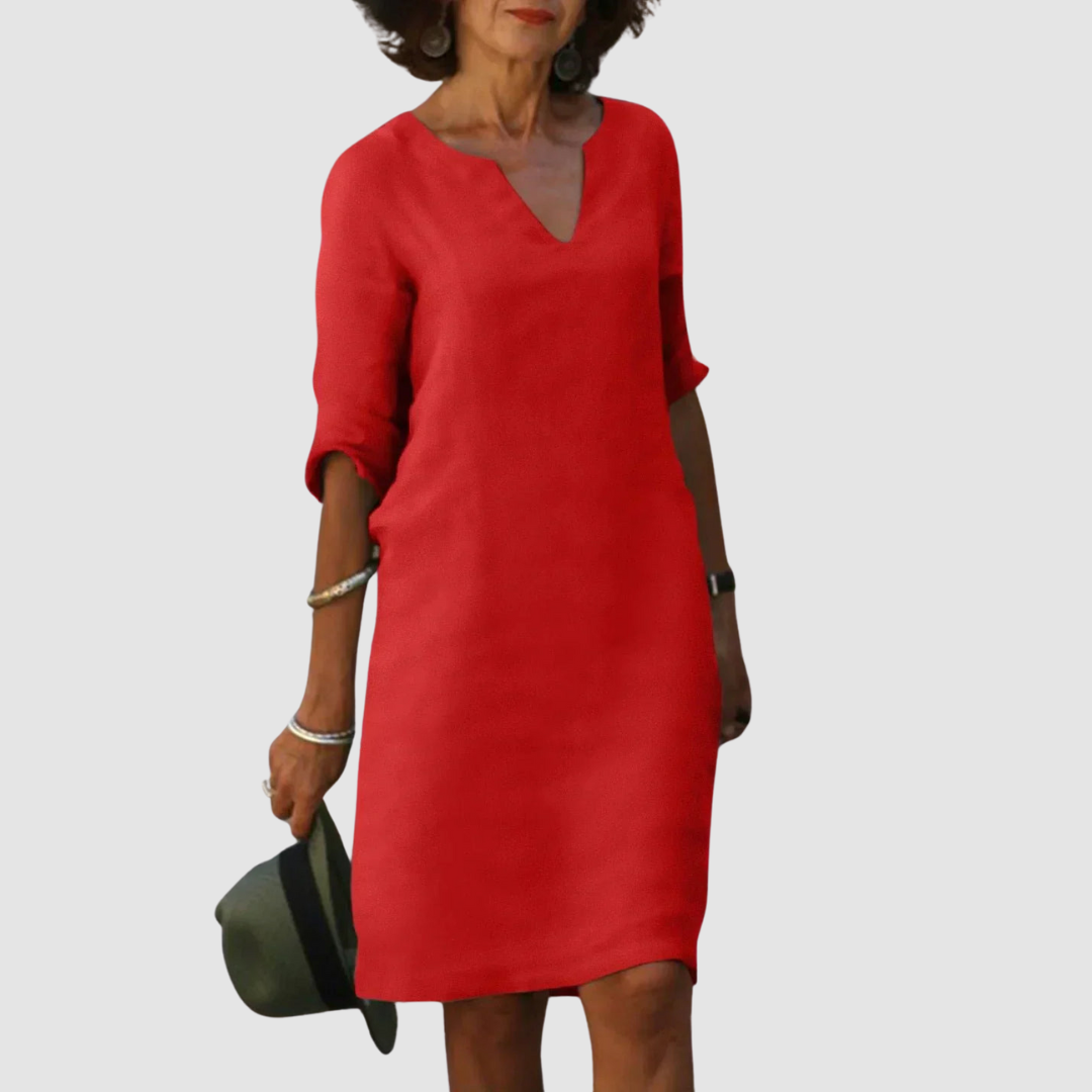 Elegant red V-neck dress with mid-length sleeves, modeled with hat and jewelry on neutral background.