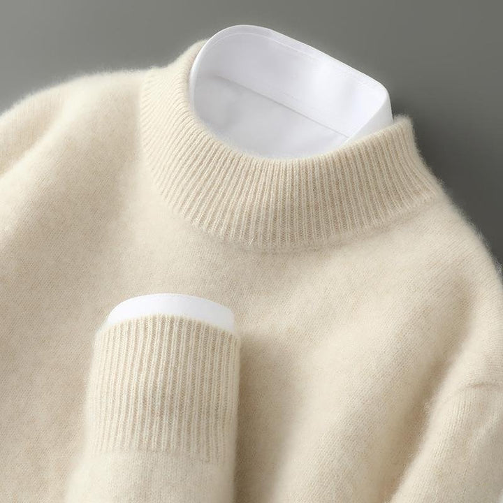 Close-up of a soft, cream-colored sweater with a ribbed turtleneck and cuff on a neutral background.