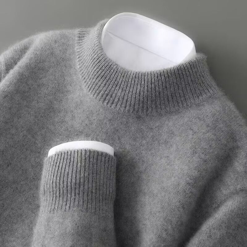Close-up of a soft, gray sweater with a ribbed turtleneck and cuff on a gray background.