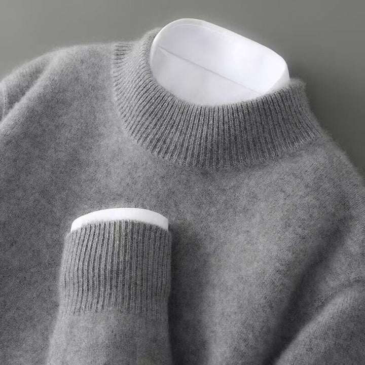 Close-up of a soft, gray sweater with a ribbed turtleneck and cuff on a gray background.
