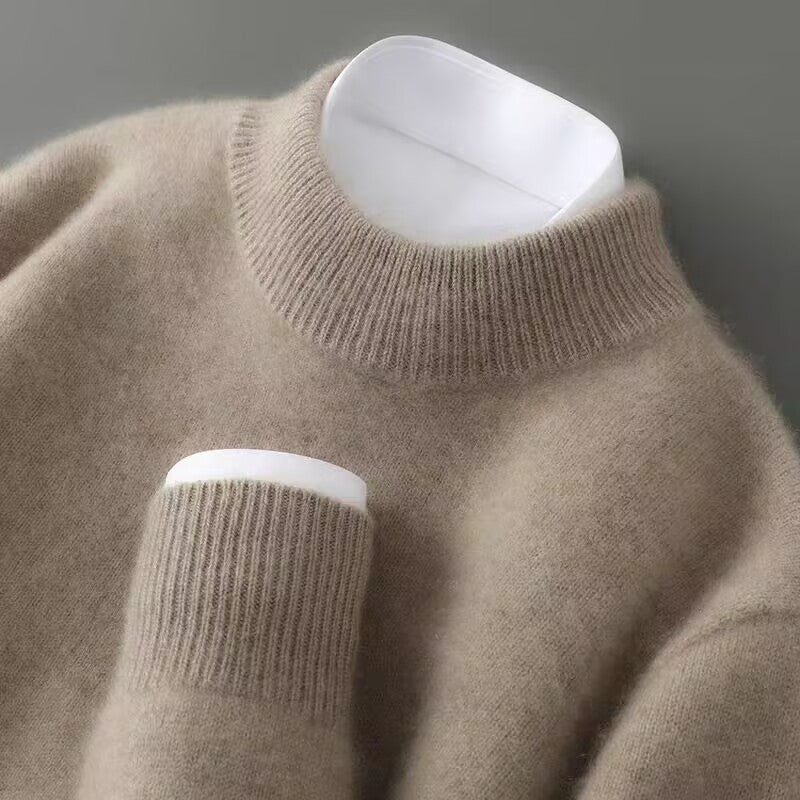 Close-up of a soft, taupe sweater with a ribbed turtleneck and cuff on a neutral background.