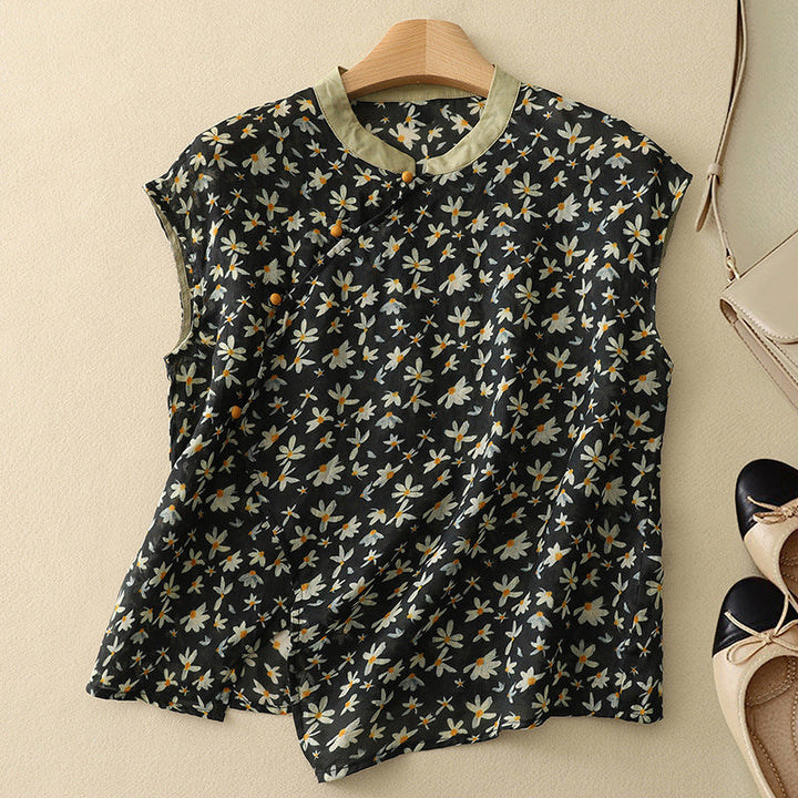 Black floral sleeveless top on a hanger, with soft texture, set against a light background with shoes and a bag.