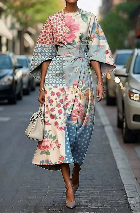 Colorful patchwork dress with florals and polka dots, kimono sleeves, belted waist, modeled on a city sidewalk.