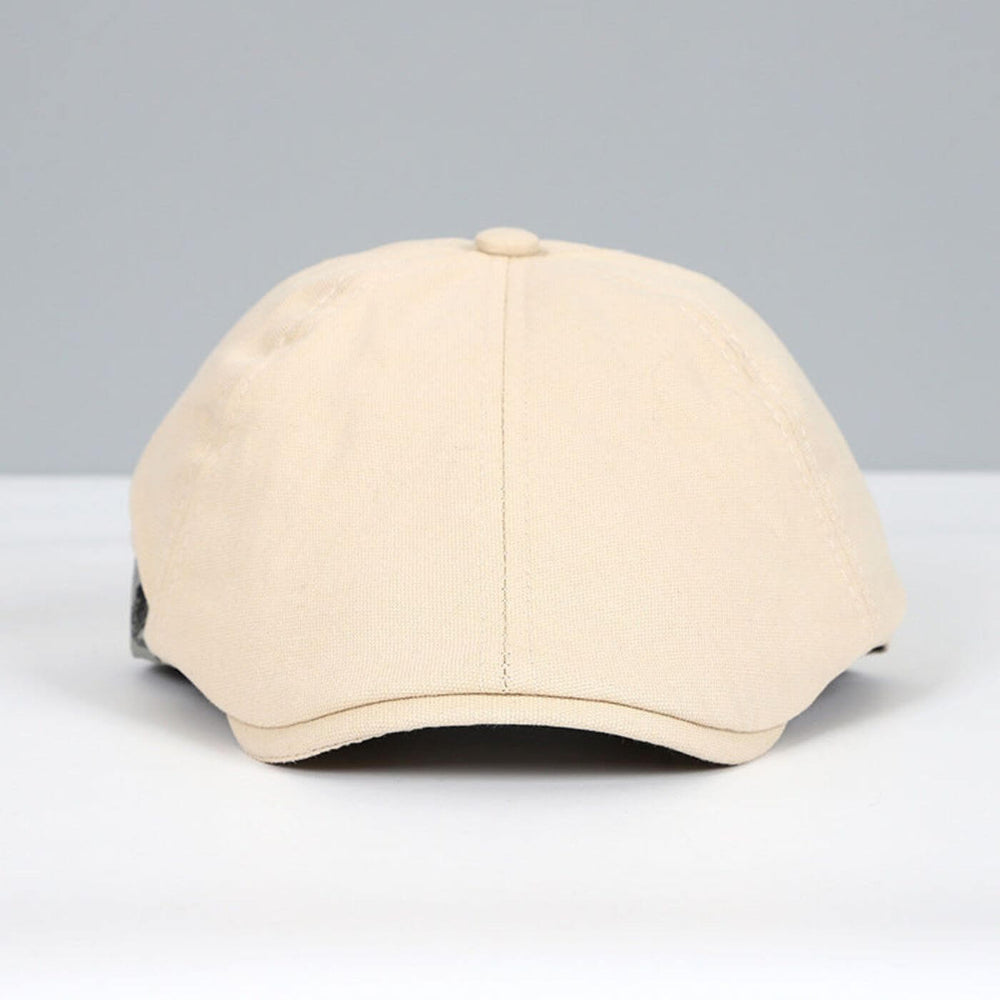 Front view of beige flat cap with a sleek, soft design on a grey and white backdrop.