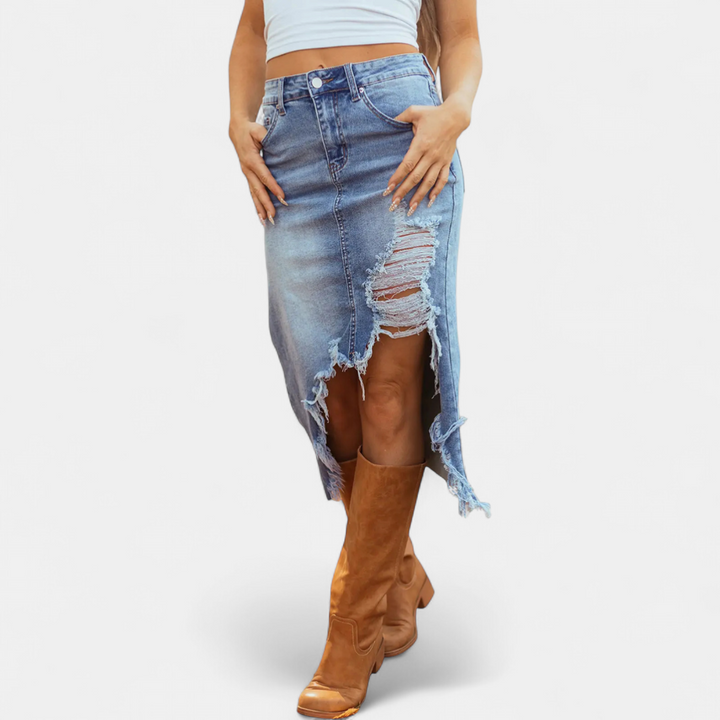 Front view of a distressed high-waist denim maxi skirt with a white top and brown boots in a studio setting.