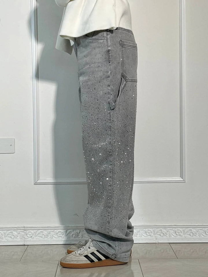 Side profile of gray diamond-detailed trousers with striped sneakers in a light-filled studio.