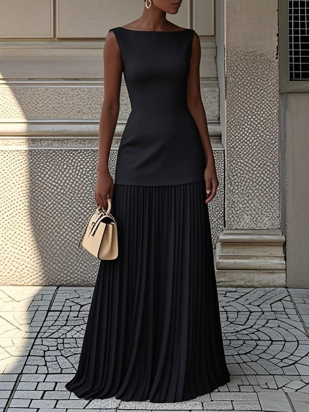 Sophisticated black pleated maxi dress featuring a fitted bodice, complemented by a beige handbag on paved city backdrop.