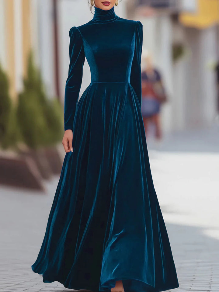 Elegant blue velvet dress with long sleeves and flowing skirt, worn in a chic urban setting.