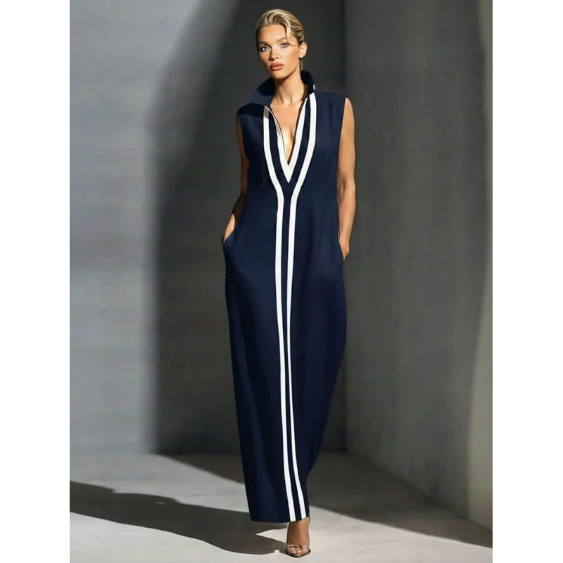 Elegant navy sleeveless maxi dress with white stripes in a minimalist indoor setting.