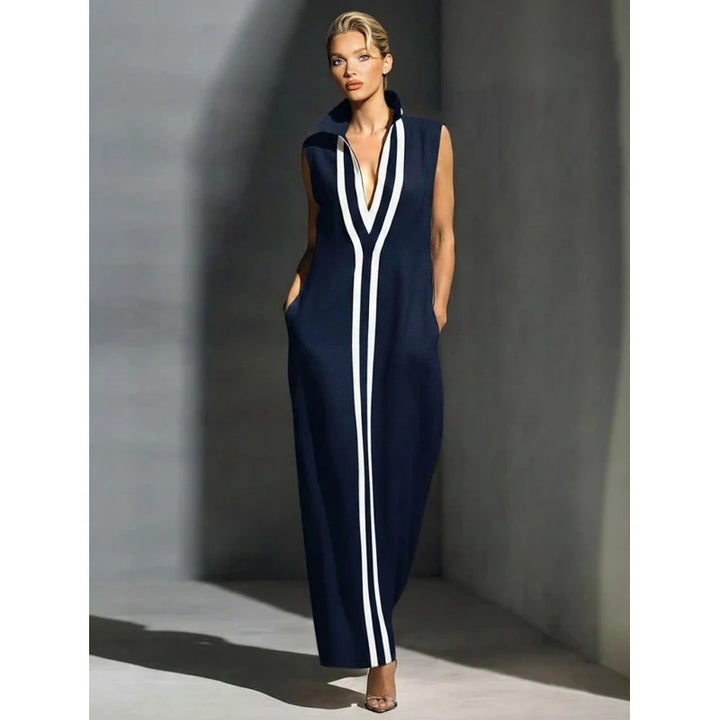 Elegant navy sleeveless maxi dress with white stripes in a minimalist indoor setting.